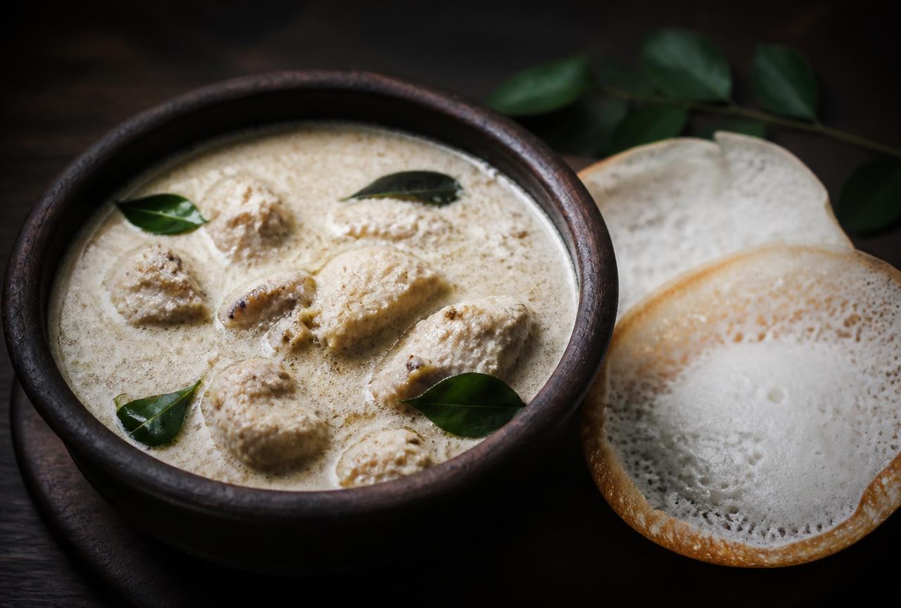 Kerala chicken mappas curry in a clay pot with curry leaves and appam